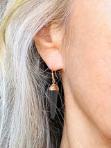 Earrings by Susan Crow Studio, Bullet shaped genuine Black Jet Gemstones in a hand carved and cast recycled 14kt yellow gold drop earrings, one of a kind. 1" long. shown on a model.