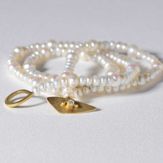 The Pearl Toggle Necklace consists of 17” of varying sized freshwater pearls hand knotted with silk thread. It’s handmade one of a kind toggle clasp is highlighted with a round bezel set diamond.