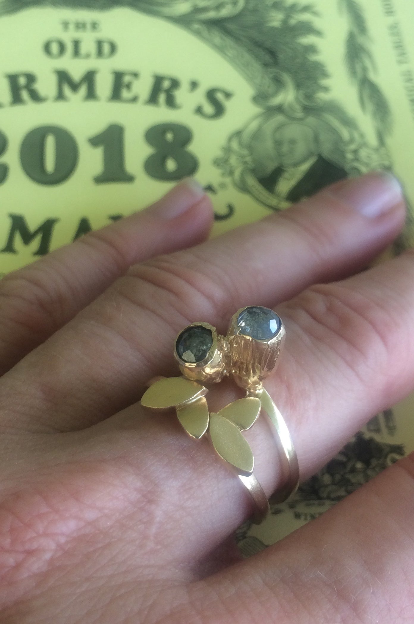 Our Double Pod Diamond Ring. Hand carved and cast in recycled 14kt yellow gold. Set with 2 rose cut black diamonds. Soft cashmere brushed finish. Available to ship in a size 7. Shown stacked with another ring