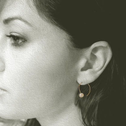 Simple 18kt and pearl open hoop earring. 7mm round pearls 1 on each hoop earring 1.25" x .5". Shown on model.
