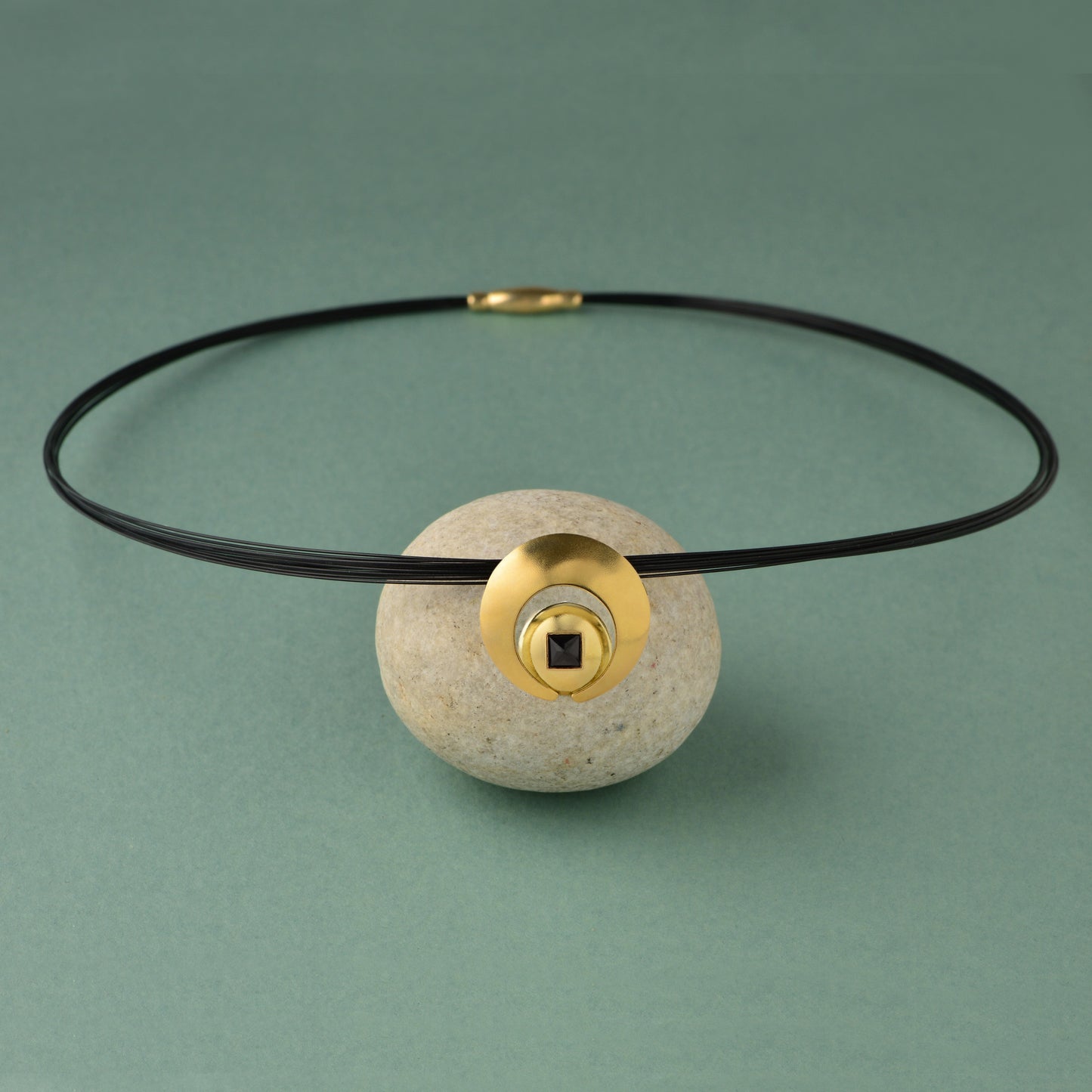 The Moon Pendant has a 4mm genuine square cut Black Spinel gemstone and the multiple circle dome shaped pieces make up the pendant . it is approximately 1" in diameter and hangs from a 17” multi strand black ruthenium plated sterling silver collar with a 14kt gold barrel clasp.