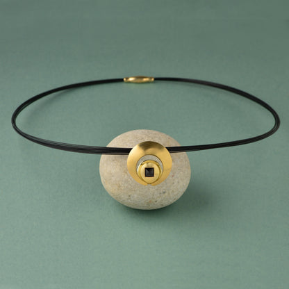 The Moon Pendant has a 4mm genuine square cut Black Spinel gemstone and the multiple circle dome shaped pieces make up the pendant . it is approximately 1" in diameter and hangs from a 17” multi strand black ruthenium plated sterling silver collar with a 14kt gold barrel clasp.